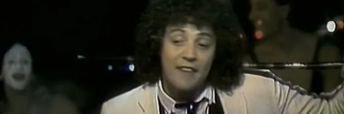 Patrick Hernandez e a história de gravação de Born to Be Alive Patrick Hernandez segurando sua icônica bengala enquanto canta em um palco na década de 1970.