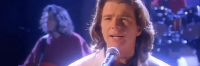 Rick Astley e a história da música Cry for Help O cantor Rick Astley cantando de forma emotiva com um grande coral gospel ao fundo durante o início dos anos 90.