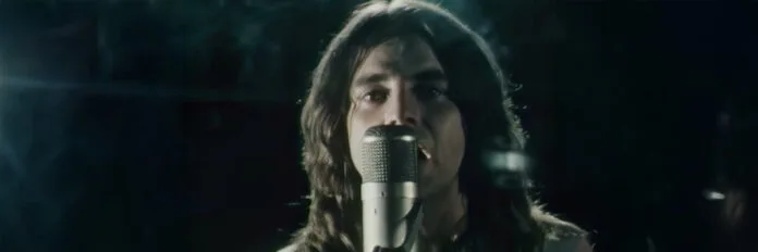A alegria contagiante de John Paul Young. O cantor John Paul Young sorrindo e cantando seu grande sucesso com um microfone na mão no final dos anos setenta.