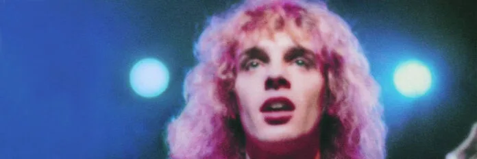 Peter Frampton tocando violão acústico no palco durante a gravação do álbum ao vivo Frampton Comes Alive em 1976.
