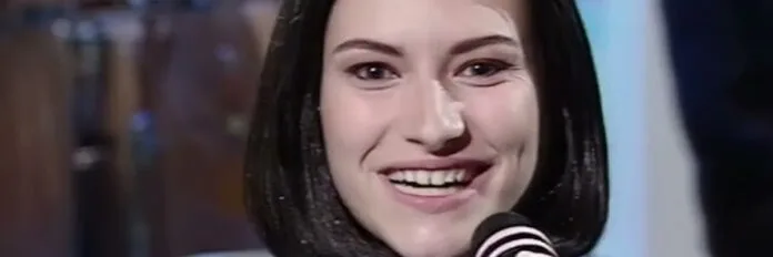 Laura Pausini e a história da música Strani Amori A cantora italiana Laura Pausini cantando emocionada com um microfone durante a sua apresentação no Festival de Sanremo nos anos 90.