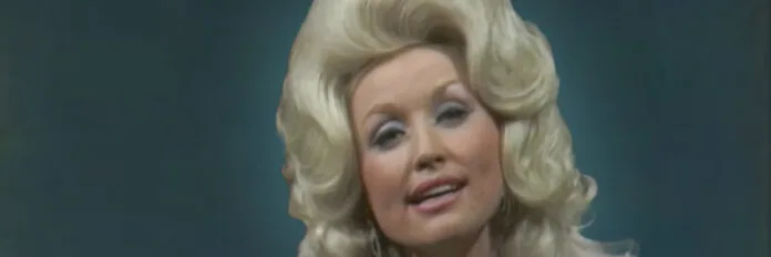 A cantora Dolly Parton sorrindo suavemente enquanto canta nos anos setenta.