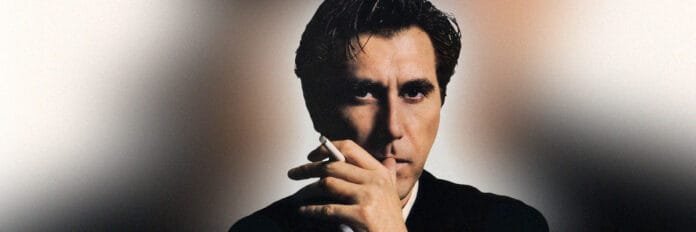 A classe de Bryan Ferry. O cantor Bryan Ferry vestindo um terno elegante e olhando de forma séria, com uma estética escura típica dos anos 80.