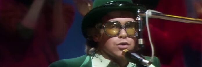 A energia de Elton John no piano. O cantor Elton John tocando piano usando seus tradicionais óculos extravagantes e roupas brilhantes na década de 70.