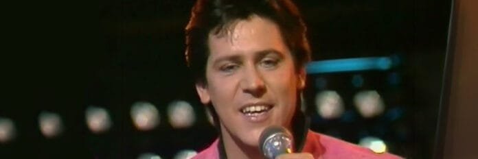 O segredo de Shakin' Stevens em performance ao vivo nos anos 80, com visual rockabilly característico, em referência ao single